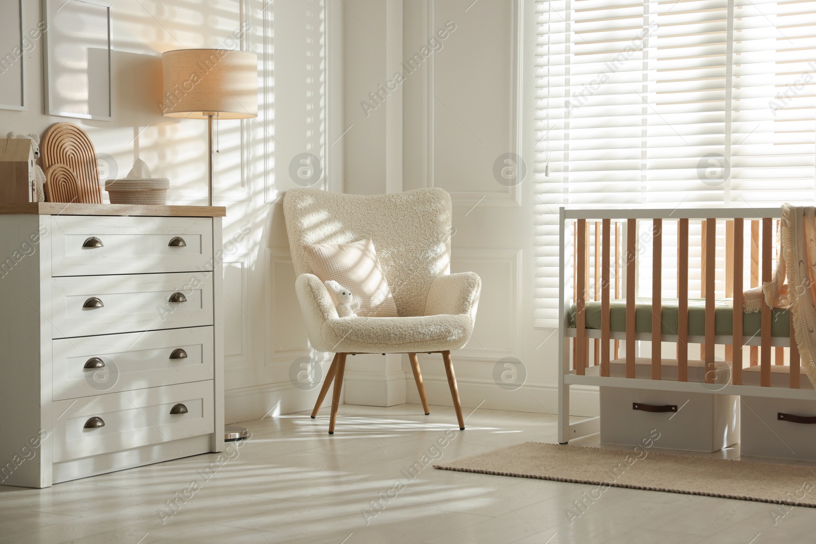 Photo of Stylish baby's room with crib and armchair. Interior design