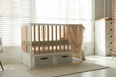 Photo of Stylish baby's room with crib and chest of drawers. Interior design