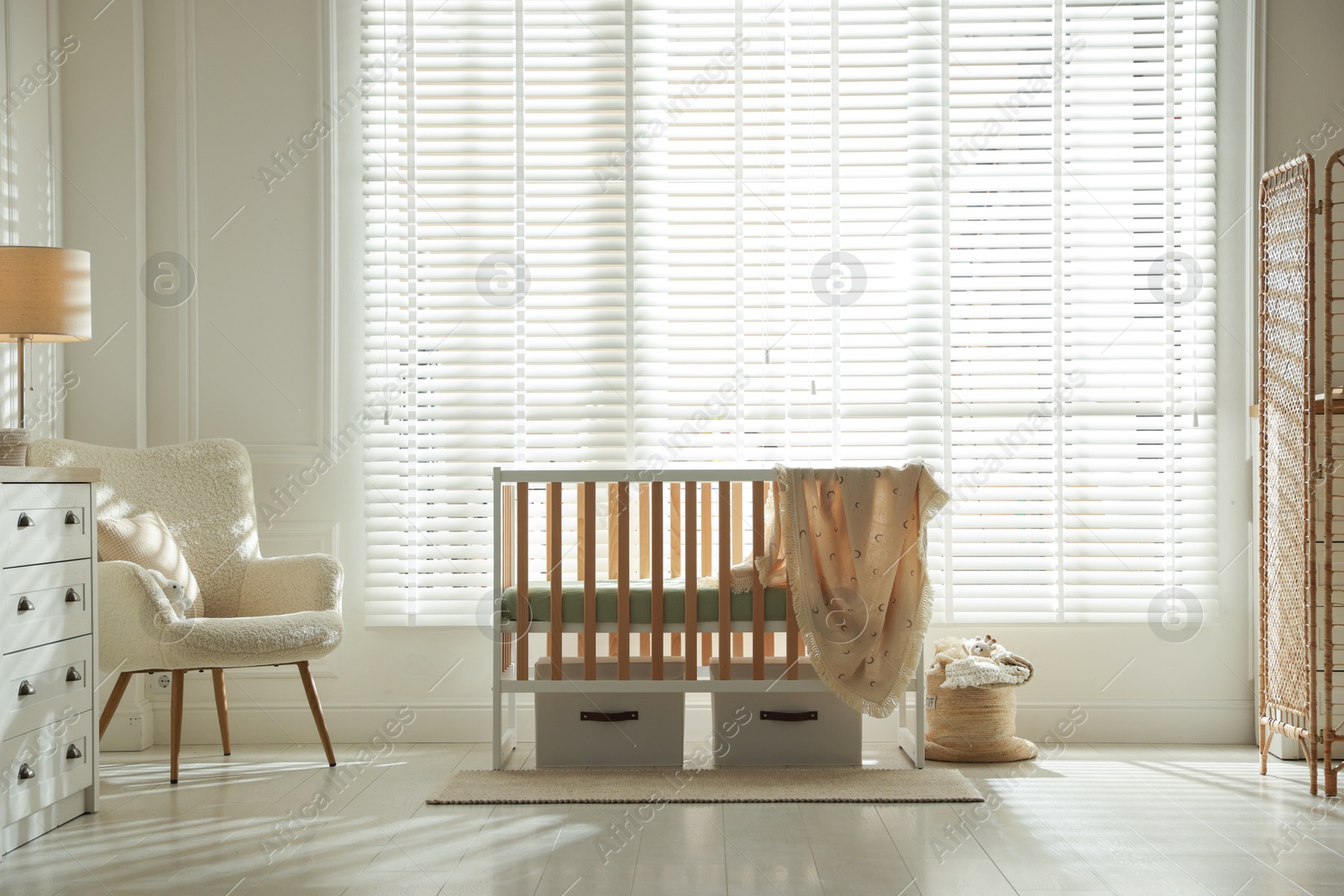Photo of Stylish baby's room with crib and armchair. Interior design
