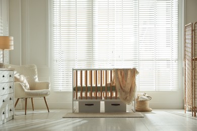 Photo of Stylish baby's room with crib and armchair. Interior design