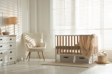 Photo of Stylish baby's room with crib and armchair. Interior design
