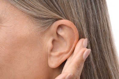 Photo of Sound. Senior woman showing hand to ear gesture on white background, closeup