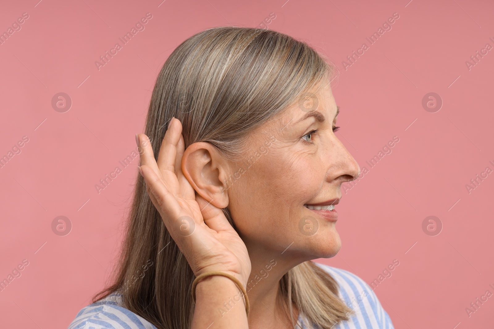 Sound. Senior woman showing hand to ear gesture on pink background Photo of Sound. Senior woman showing hand to ear gesture on pink background