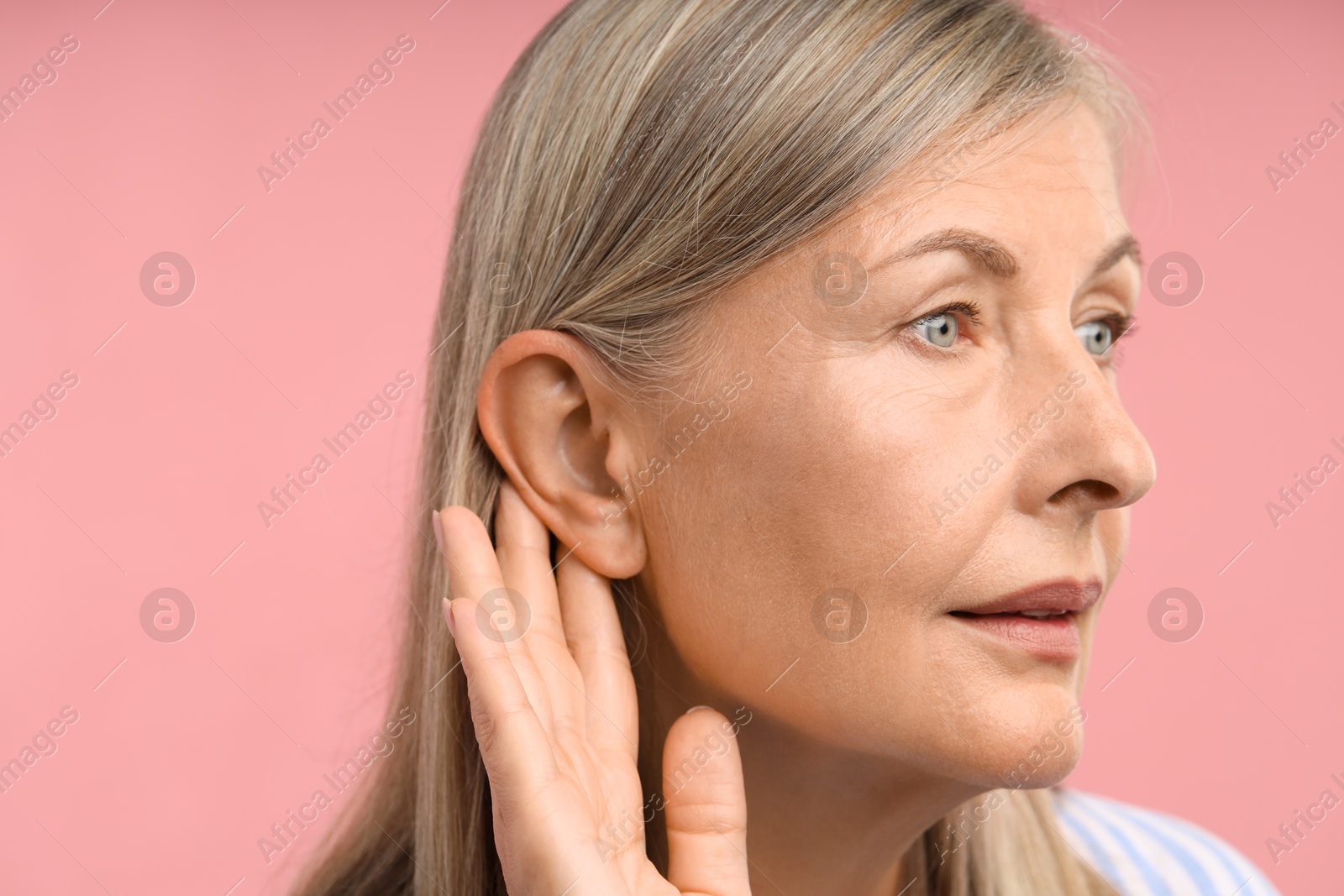 Photo of Sound. Senior woman touching her ear on pink background