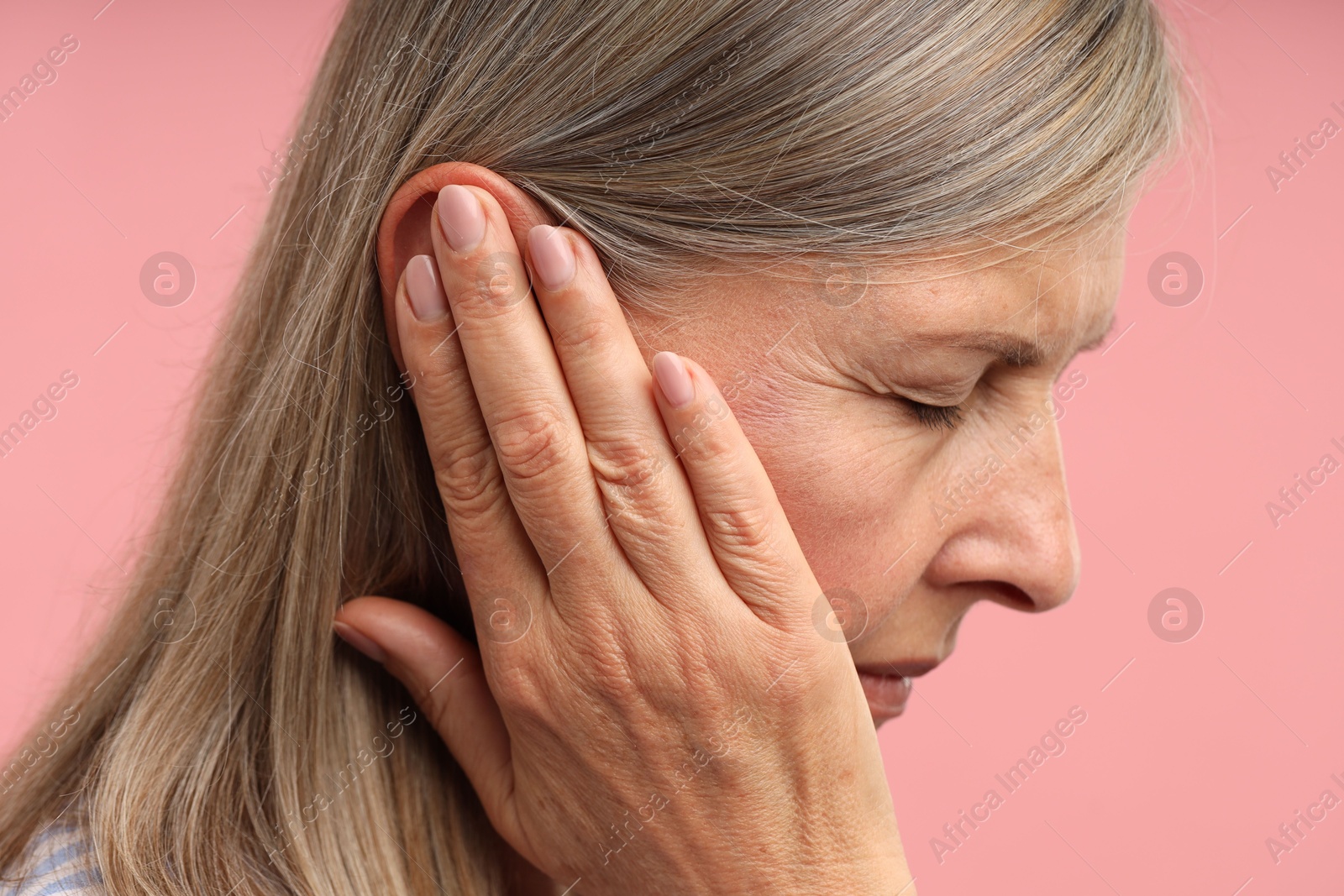Photo of Sound. Senior woman touching her ear on pink background