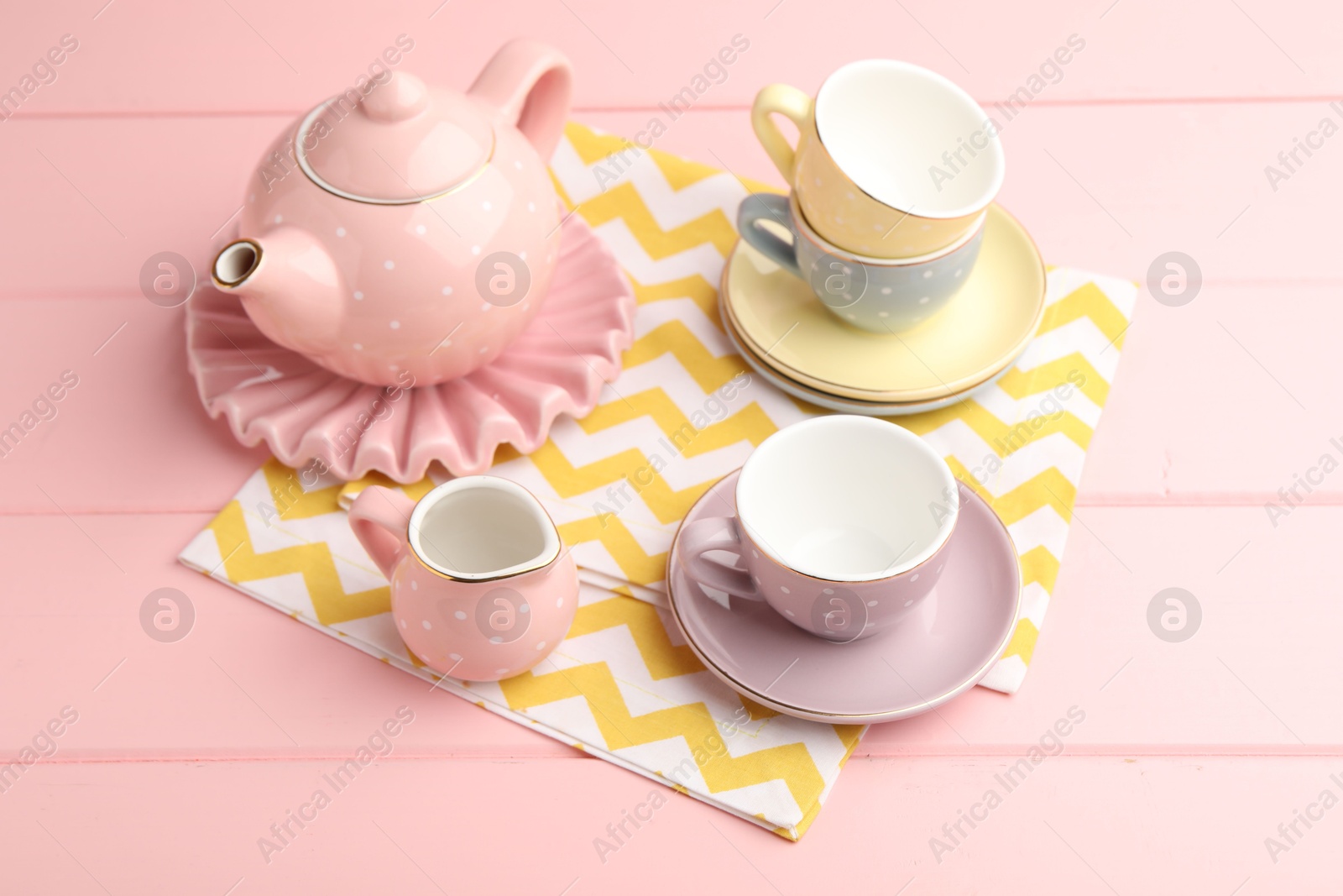 Photo of Beautiful ceramic tea set for children on pink wooden table
