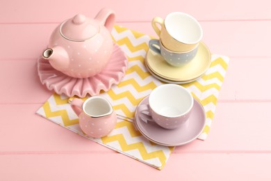 Photo of Beautiful ceramic tea set for children on pink wooden table