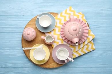 Photo of Beautiful ceramic tea set for children and napkin on light blue wooden table, top view