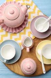 Photo of Beautiful ceramic tea set for children and napkin on light blue wooden table, top view