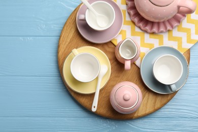 Photo of Beautiful ceramic tea set for children and napkin on light blue wooden table, top view. Space for text
