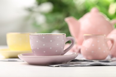 Photo of Beautiful ceramic tea set for children on white wooden table against blurred background, closeup