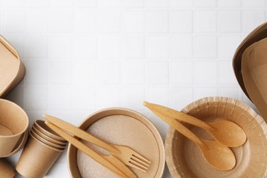 Photo of Set of disposable tableware on white tiled table, flat lay. Space for text