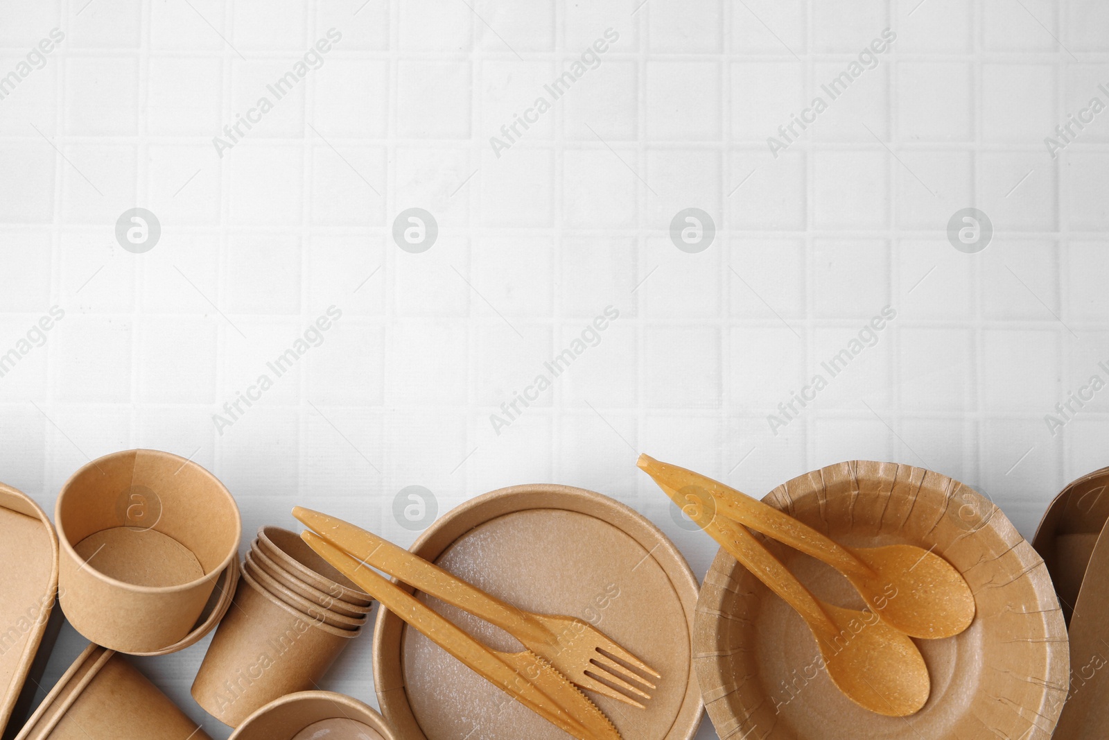 Photo of Set of disposable tableware on white tiled table, flat lay. Space for text