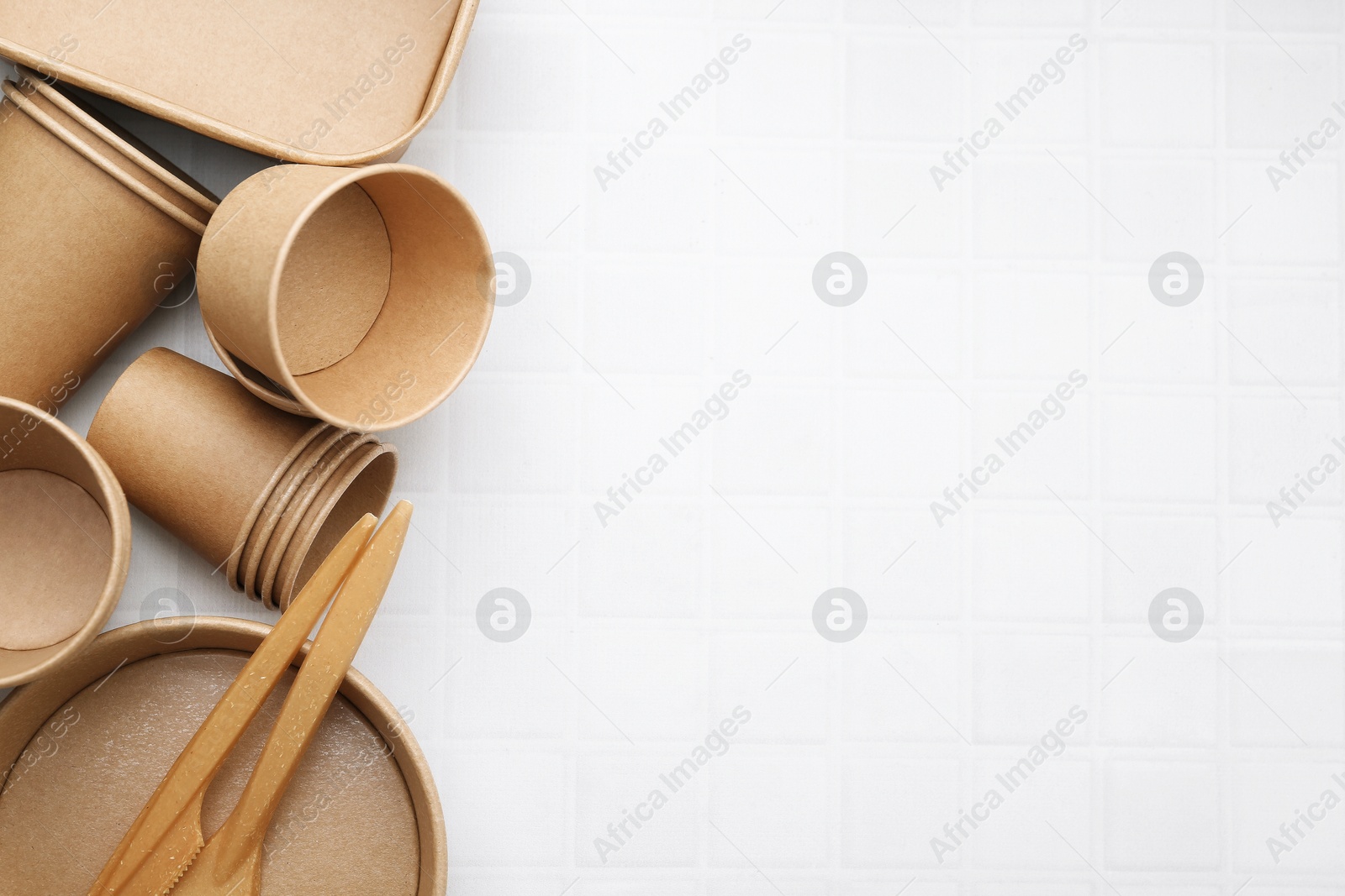 Photo of Set of disposable tableware on white tiled table, flat lay. Space for text