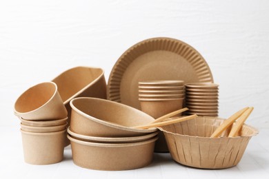Photo of Set of disposable tableware on white tiled table, closeup