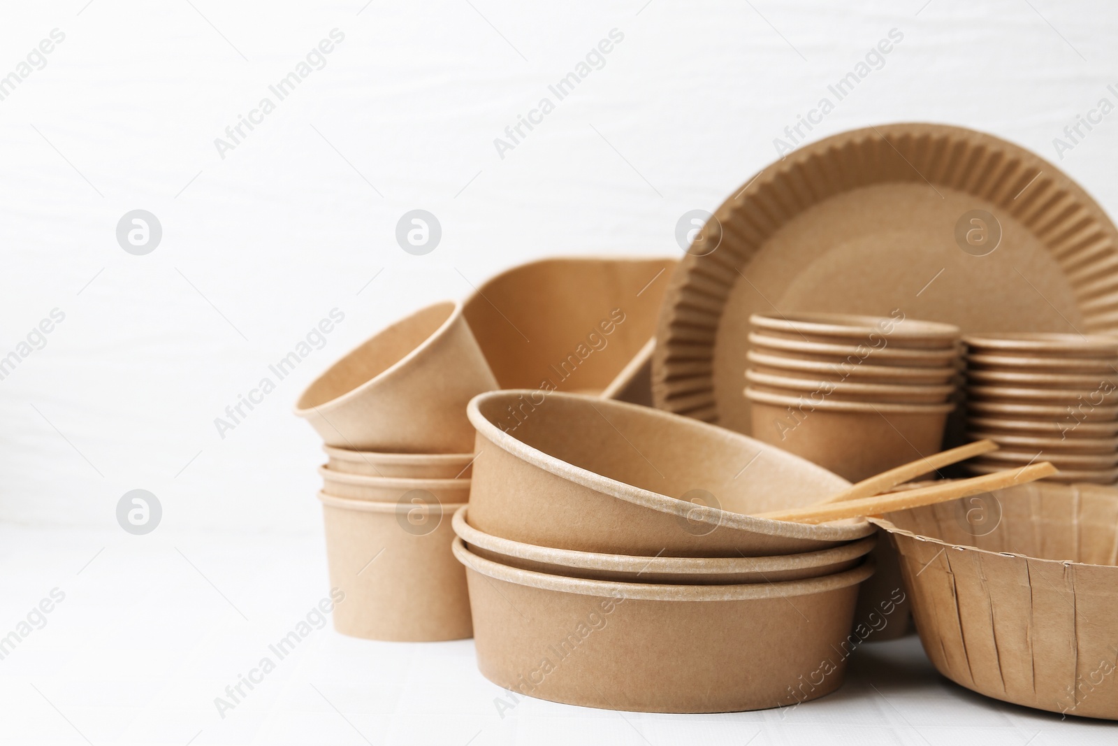 Photo of Set of disposable tableware on white table, closeup. Space for text