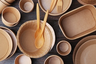 Photo of Set of disposable tableware on wooden table, flat lay
