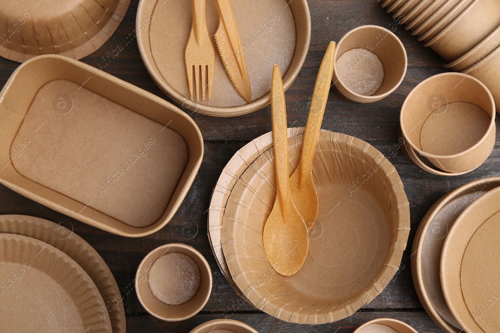 Photo of Set of disposable tableware on wooden table, flat lay
