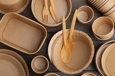 Photo of Set of disposable tableware on wooden table, flat lay