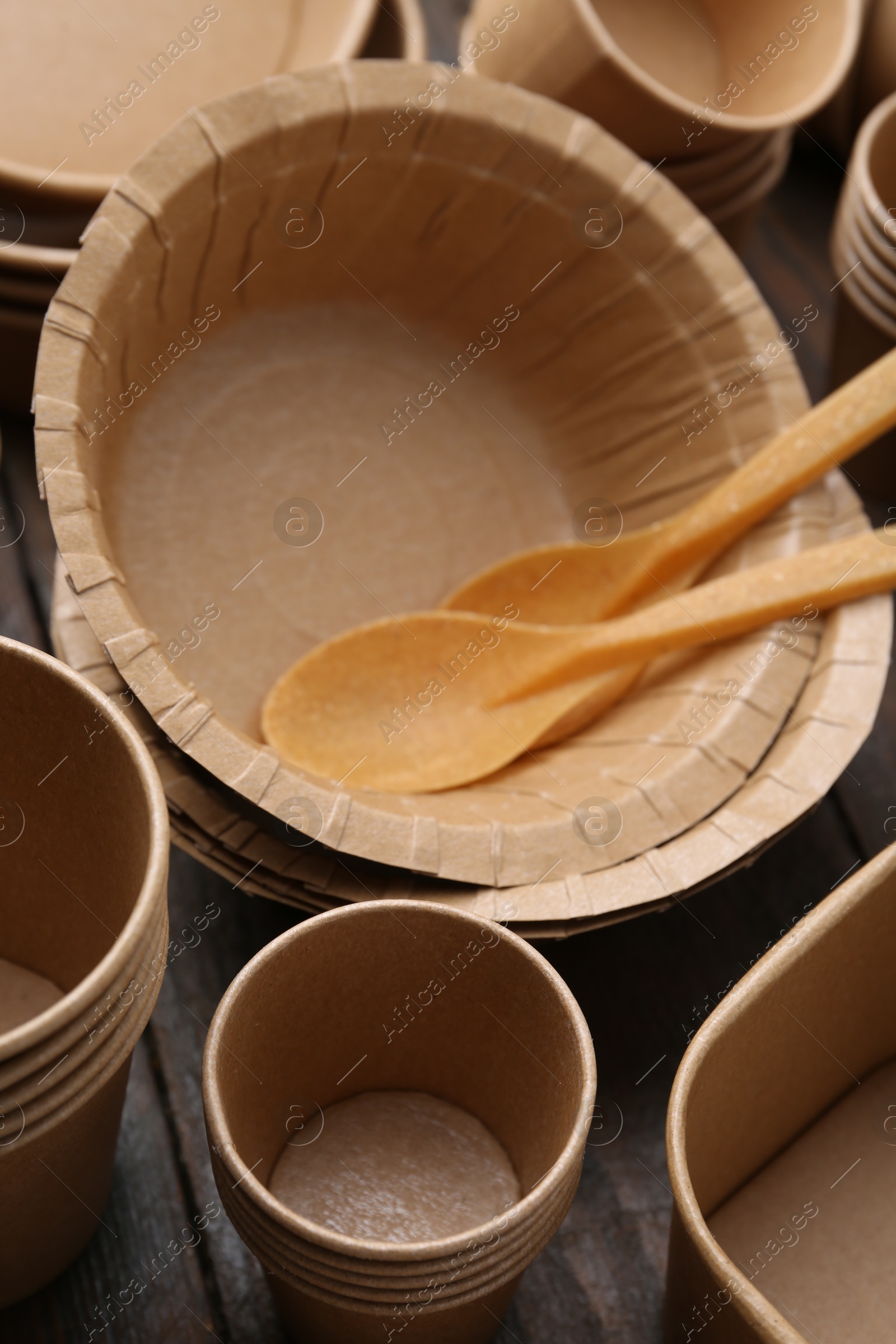 Photo of Set of disposable tableware on wooden table, closeup
