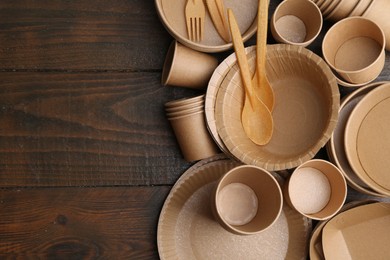 Photo of Set of disposable tableware on wooden table, flat lay. Space for text