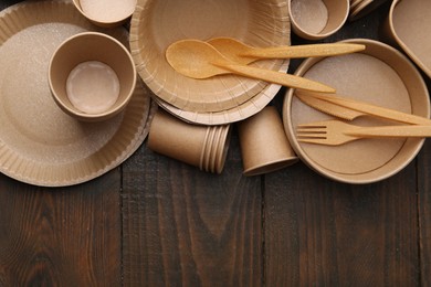 Photo of Set of disposable tableware on wooden table, flat lay. Space for text
