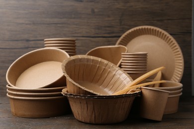 Photo of Set of disposable tableware on wooden table, closeup