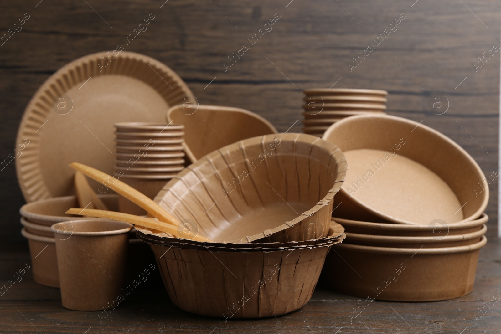Photo of Set of disposable tableware on wooden table, closeup