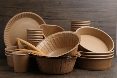 Photo of Set of disposable tableware on wooden table, closeup