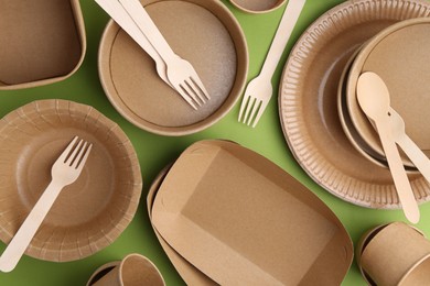 Photo of Set of disposable tableware on green background, flat lay