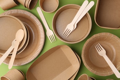Photo of Set of disposable tableware on green background, flat lay