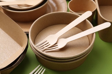 Photo of Set of disposable tableware on green background, closeup
