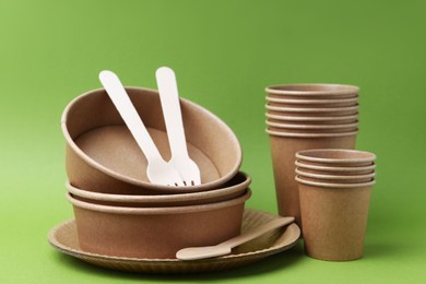 Photo of Set of disposable tableware on green background, closeup