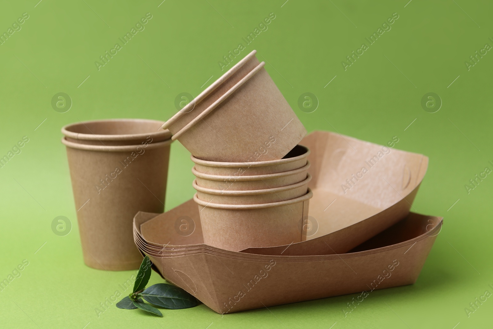Set of disposable tableware and leaves on green background, closeup Photo of Set of disposable tableware and leaves on green background, closeup