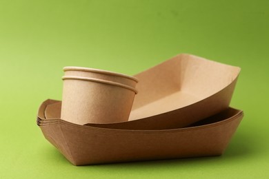 Photo of Set of disposable tableware on green background, closeup