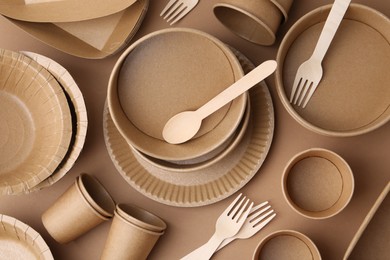 Photo of Set of disposable tableware on brown background, flat lay