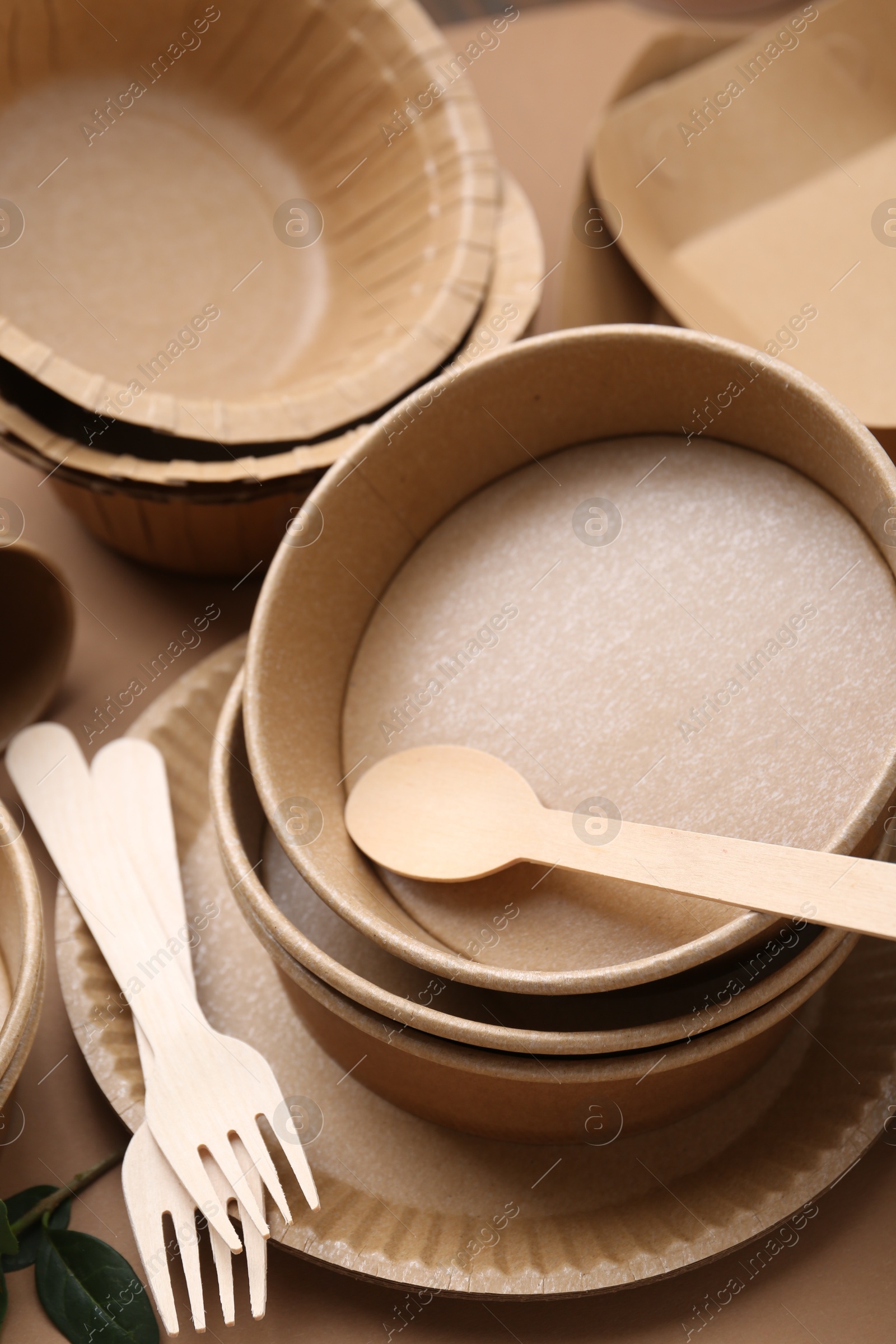 Set of disposable tableware and green leaves on brown background, closeup Photo of Set of disposable tableware and green leaves on brown background, closeup
