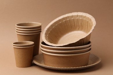 Photo of Set of disposable tableware on brown background, closeup