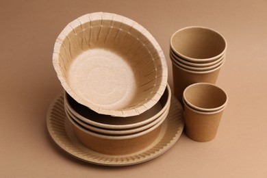 Photo of Set of disposable tableware on brown background, closeup