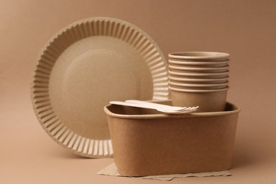 Photo of Set of disposable tableware on brown background, closeup