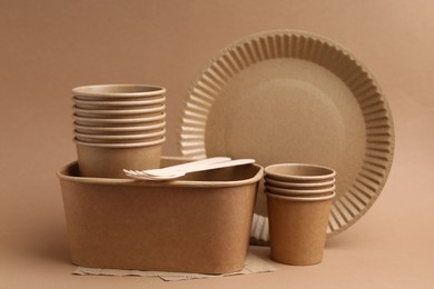 Photo of Set of disposable tableware on brown background, closeup