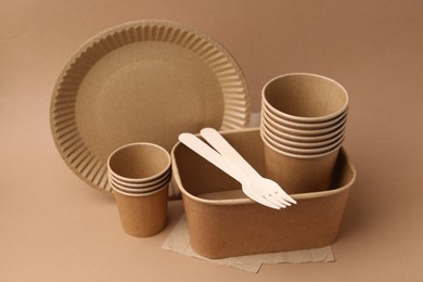 Photo of Set of disposable tableware on brown background, closeup