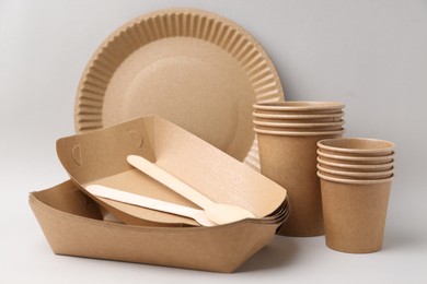 Photo of Set of disposable tableware on light grey background, closeup