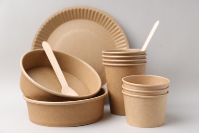 Photo of Set of disposable tableware on light grey background, closeup