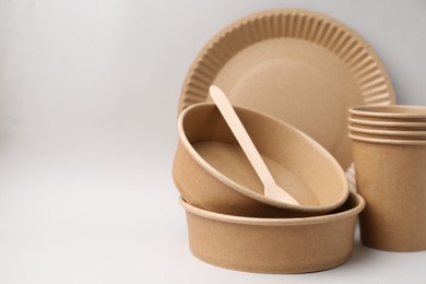 Photo of Set of disposable tableware on light grey background, closeup. Space for text