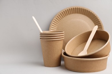 Photo of Set of disposable tableware on light grey background, closeup. Space for text