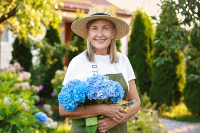 Photo of Senior woman with beautiful bouquet of flowers and pruner in garden