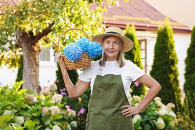 Photo of Senior woman with wicker basket of flowers in garden