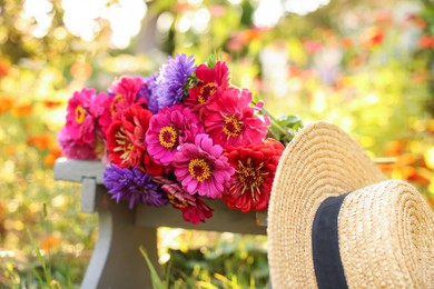 Photo of Bouquet of flowers on stool and wicker hat outdoors, closeup