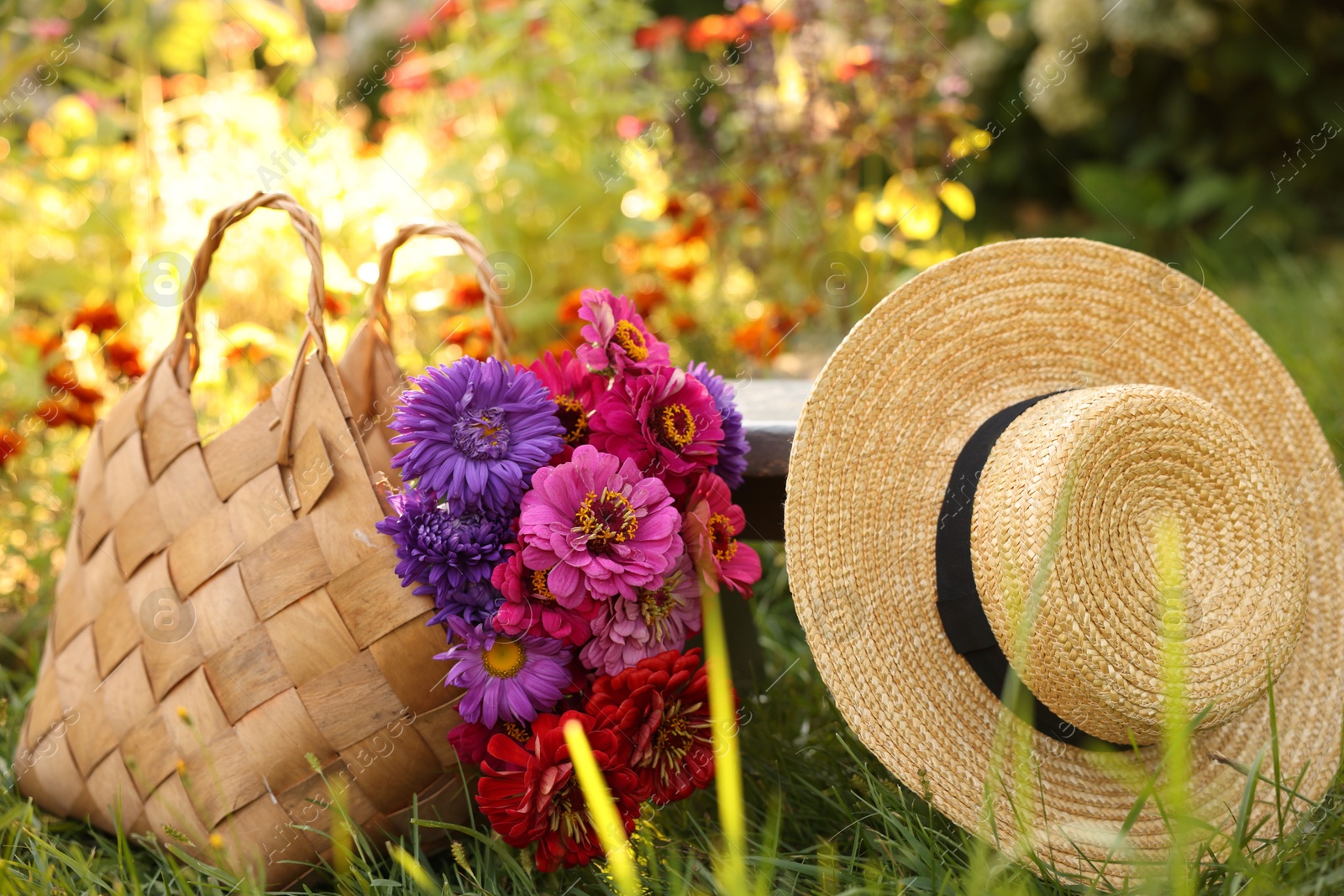 Bouquet of flowers in bag and wicker hat on green grass outdoors Photo of Bouquet of flowers in bag and wicker hat on green grass outdoors